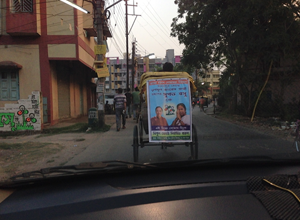 A rickshaw carries a campaign poster.